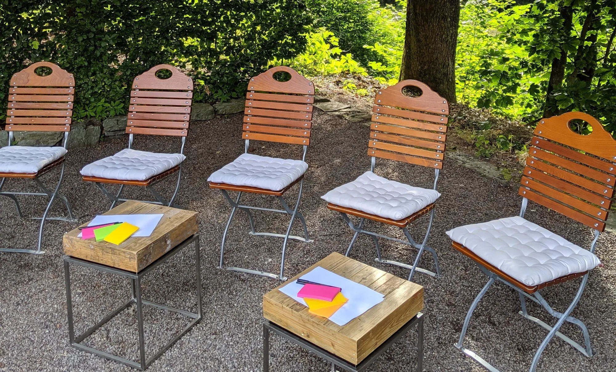 Leere Stuhlreihe mit Notizkarten vor dem Start einer GMC-Arbeitssession im Garten