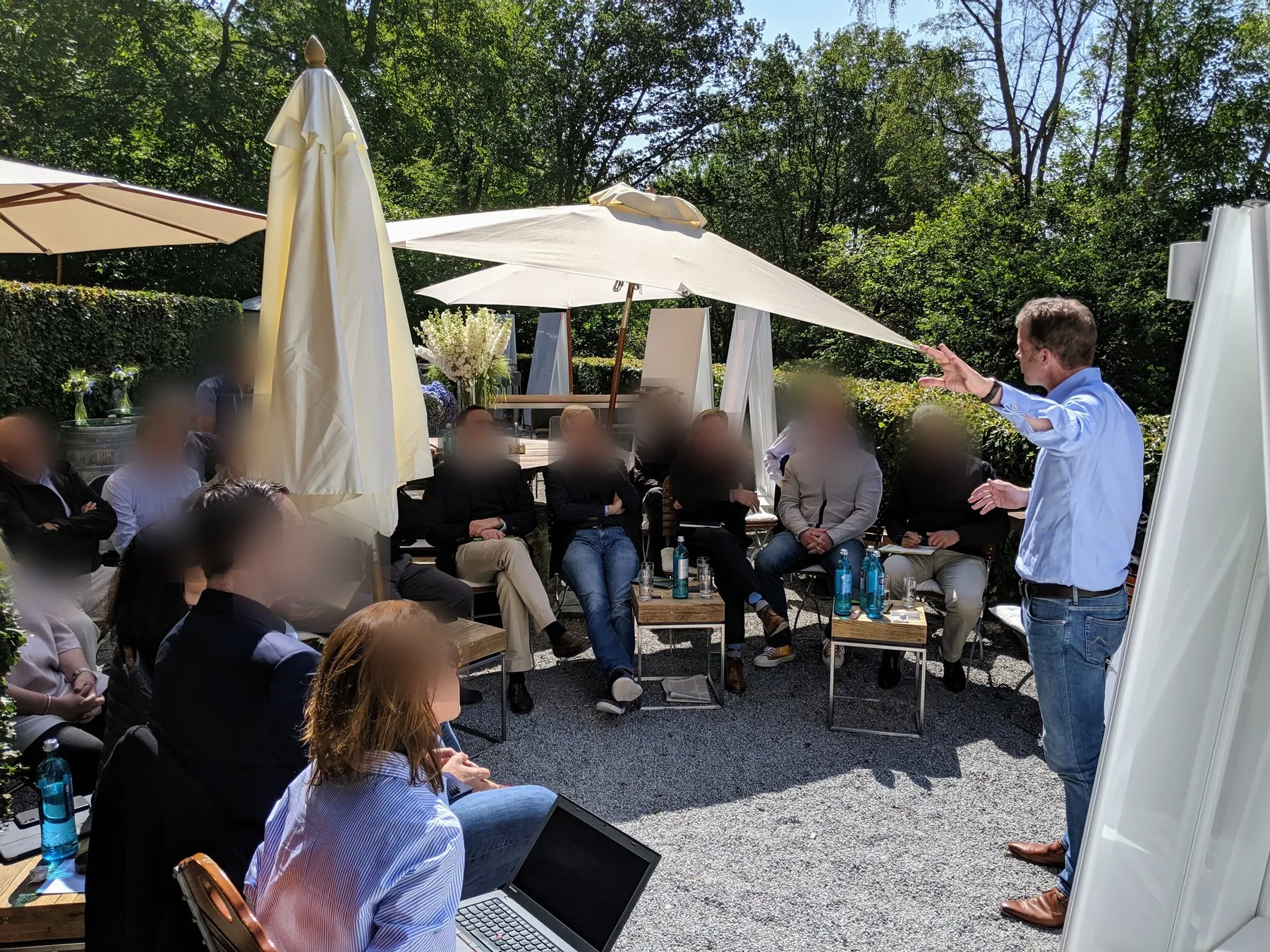 Forever Day One moderiert eine Arbeitssession des GMC der Deutschen Bank im Garten; die Gesichter der Teilnehmenden sind zum Schutz der Vertraulichkeit unkenntlich gemacht