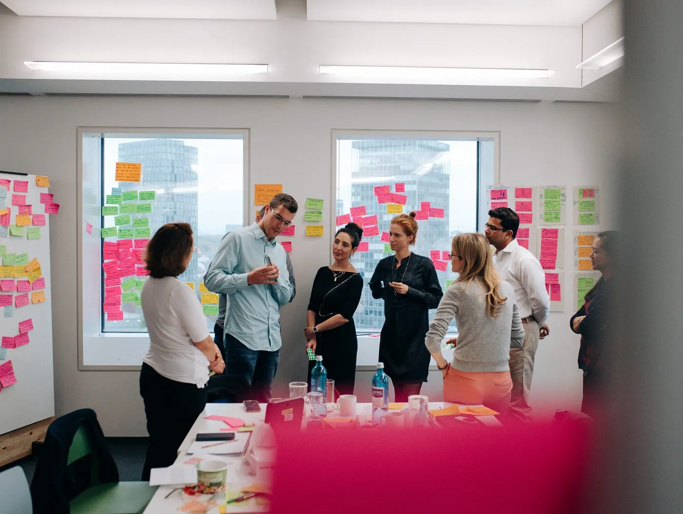 Interdisziplinäres Team der Initiative im Austausch vor einer mit Ideen-Post-its beklebten Fensterfront
