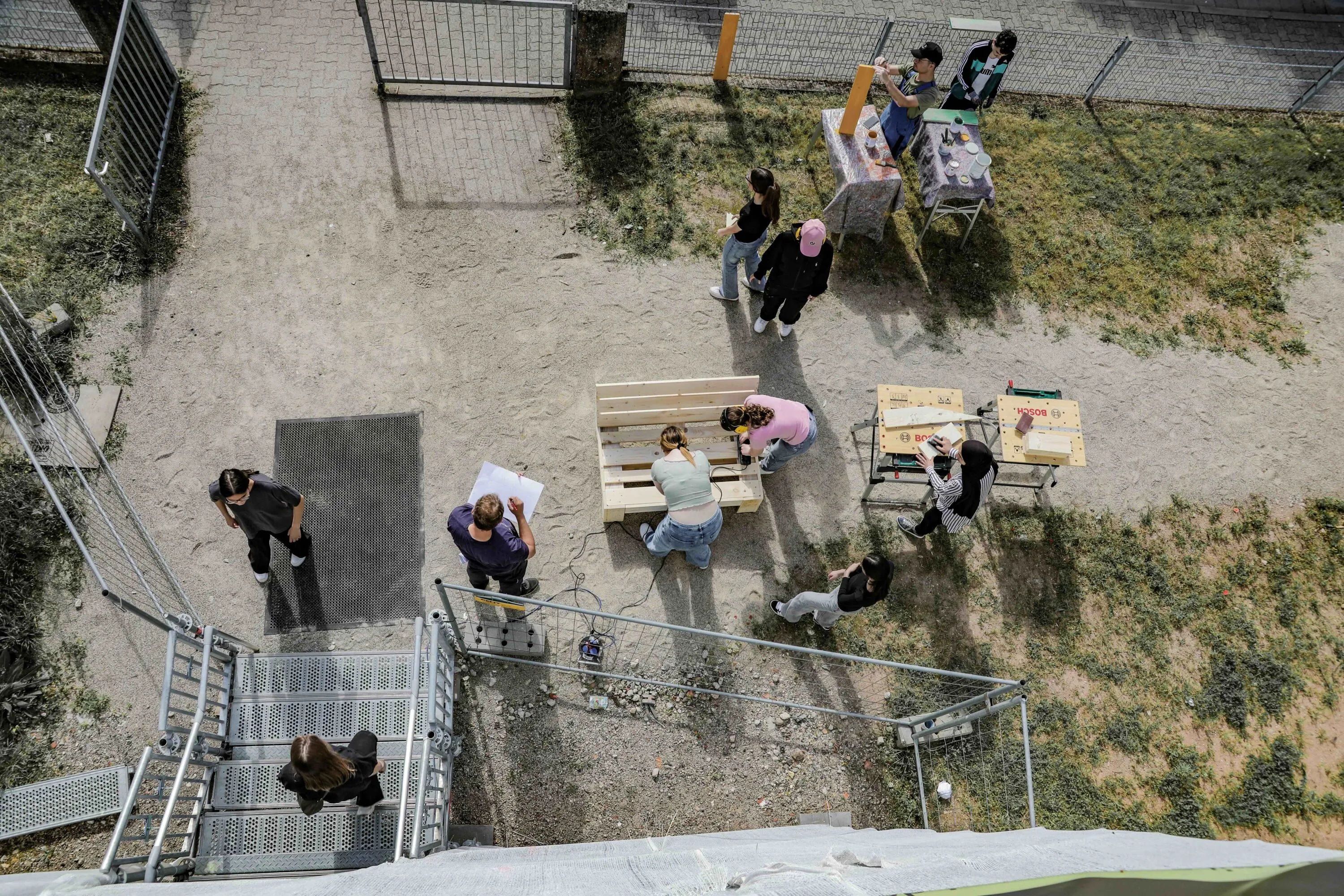 Luftaufnahme eines HORNBACH-macht-Schule-Workshops: Jugendliche bauen Möbel im Hof