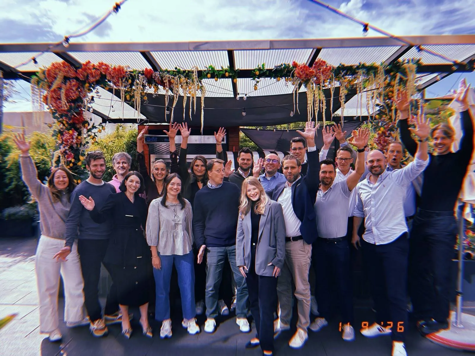 Gruppe von Teilnehmenden winkt gemeinsam auf einer Terrasse