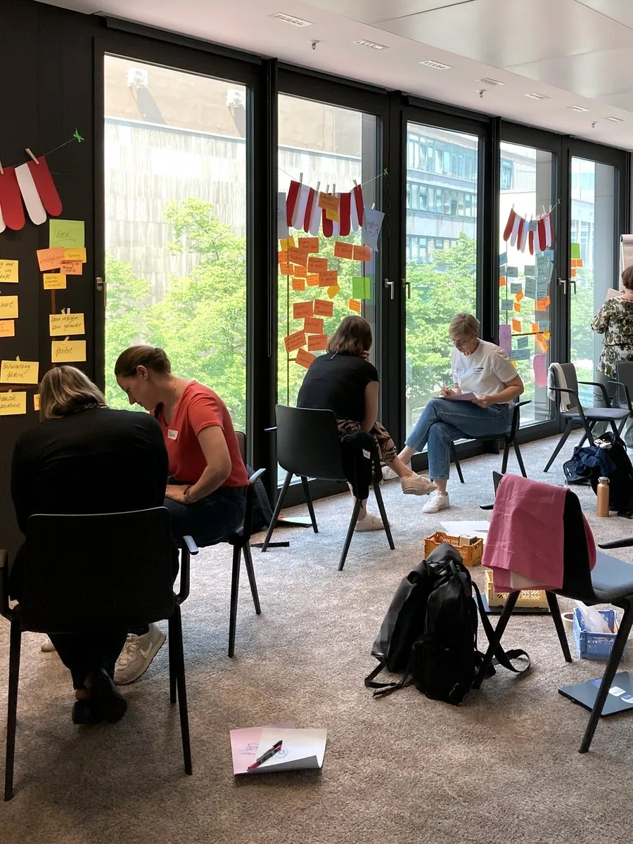 Teilnehmende arbeiten im Zielbild-Workshop von Union Investment an einer Wand voller Ideen-Post-its